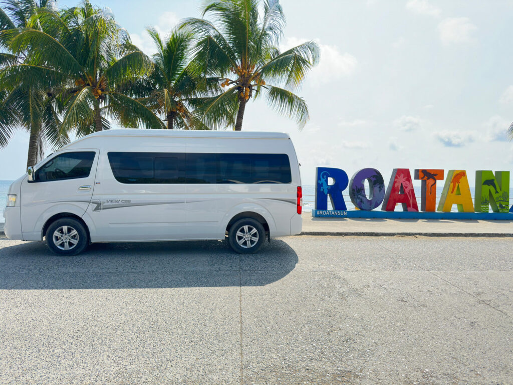 AT21 private van at the Roatán sign